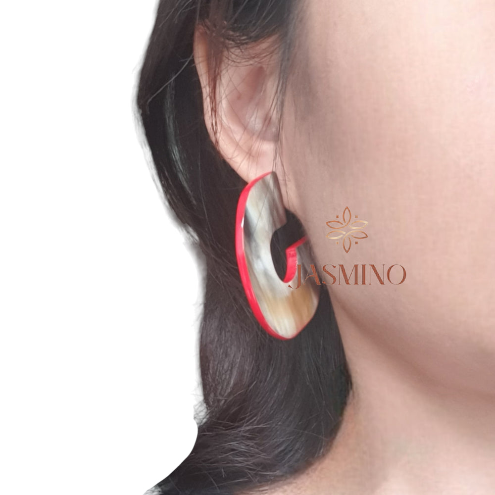 
                  
                    a model wearing handmade C shaped stud earrings feature scarlet red in natural buffalo horn for Spring 2024
                  
                