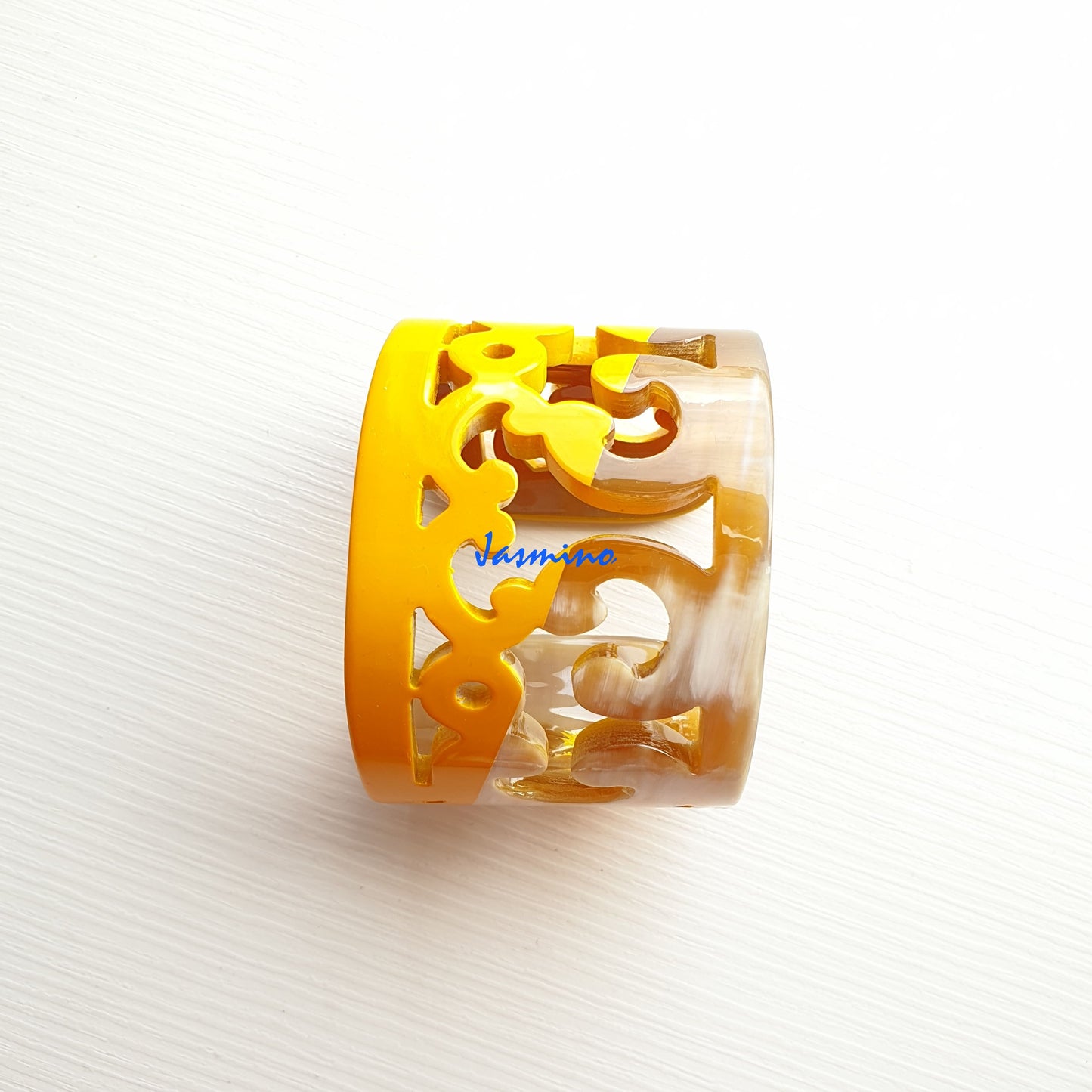 A handmade cuff bracelet features yellow and brown color and natural buffalo horn material engraved exquisitely 