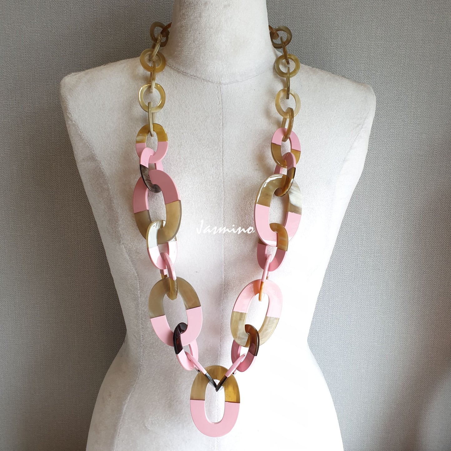 a unique buffalo horn necklace with half of big elliptical horn pieces painted light pink on a light background, impressive gift for her