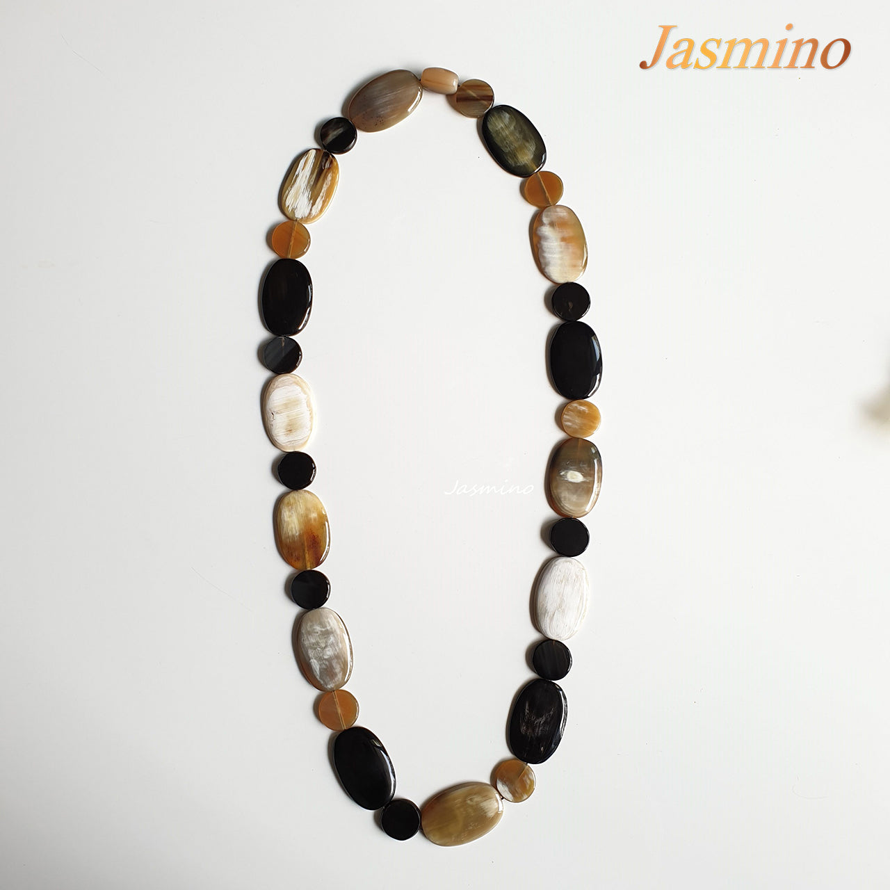 The necklace is made from a chain of natural buffalo horn pieces on the light background, unique gift for your friend