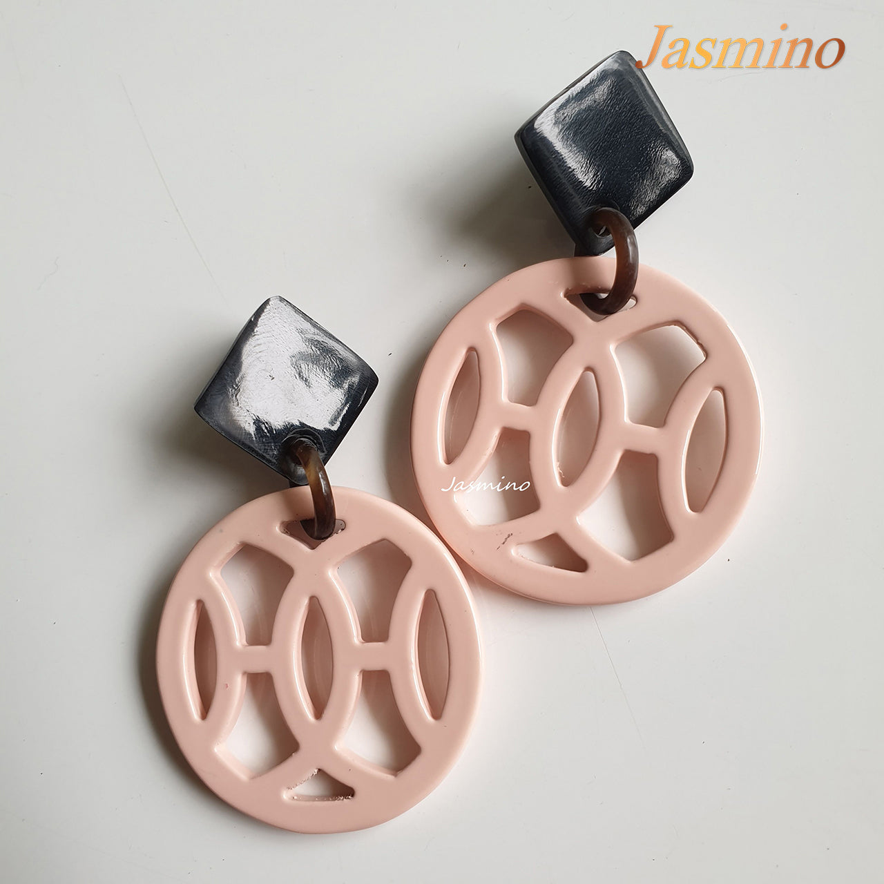 Handmade drop earrings are designed by a window shape and coral pink color with natural buffalo horn