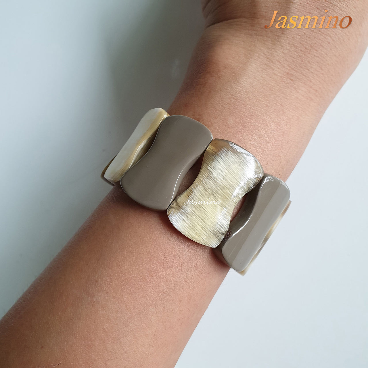 A model is wearing Jasmino unique handmade bangle bracelet featured grey in natural buffalo horn for women's gifts