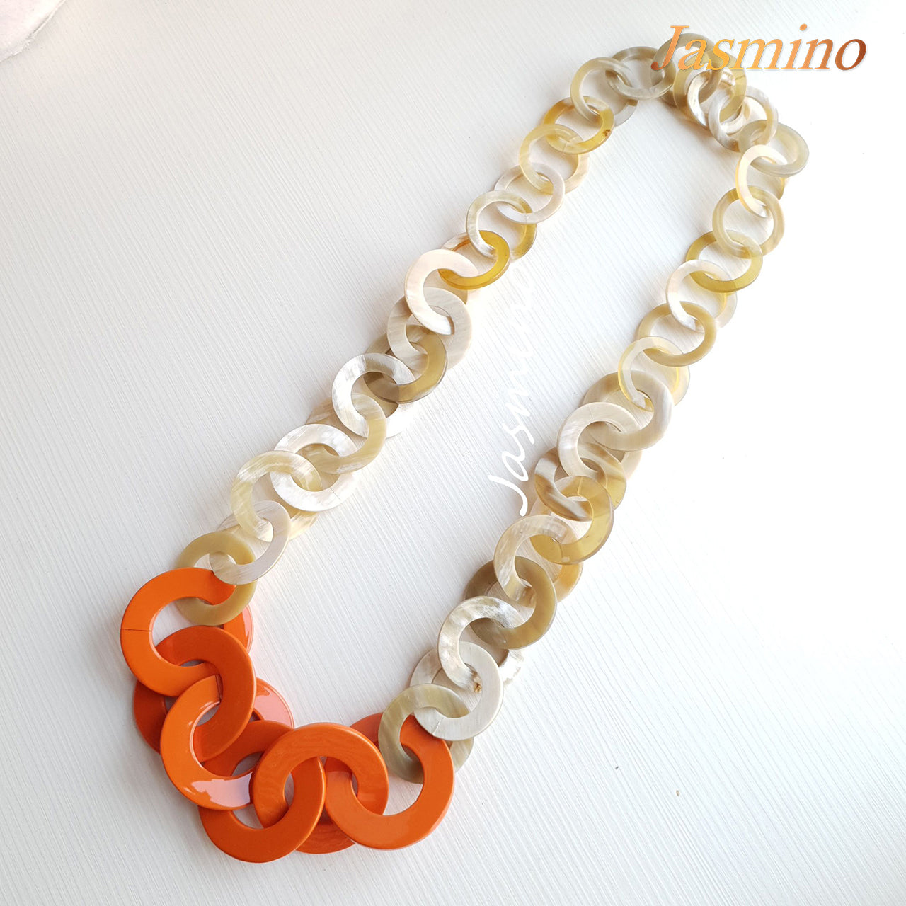 Orange peel necklace made from a series of lacquered circular horn pieces on a light background, an impressive gift for her