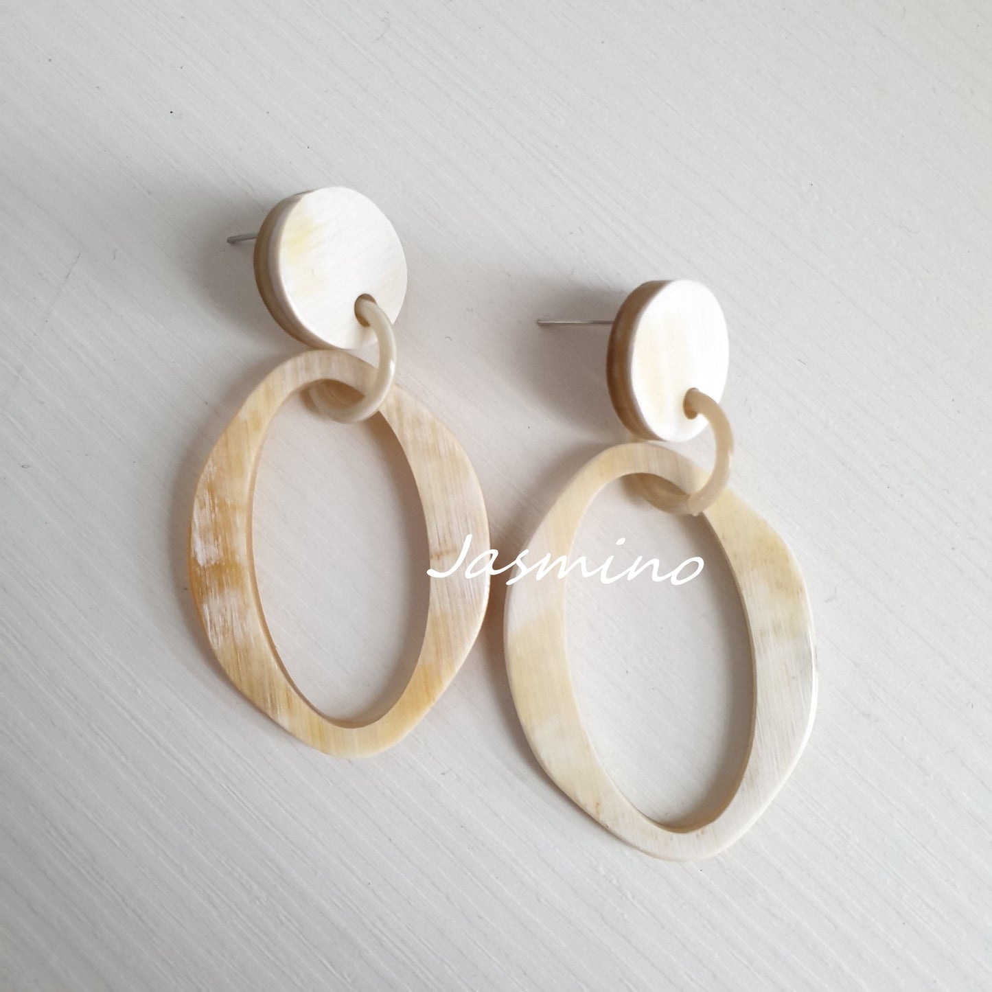 Jasmino elliptical drop earrings feature white and natural buffalo horn material in the natural light