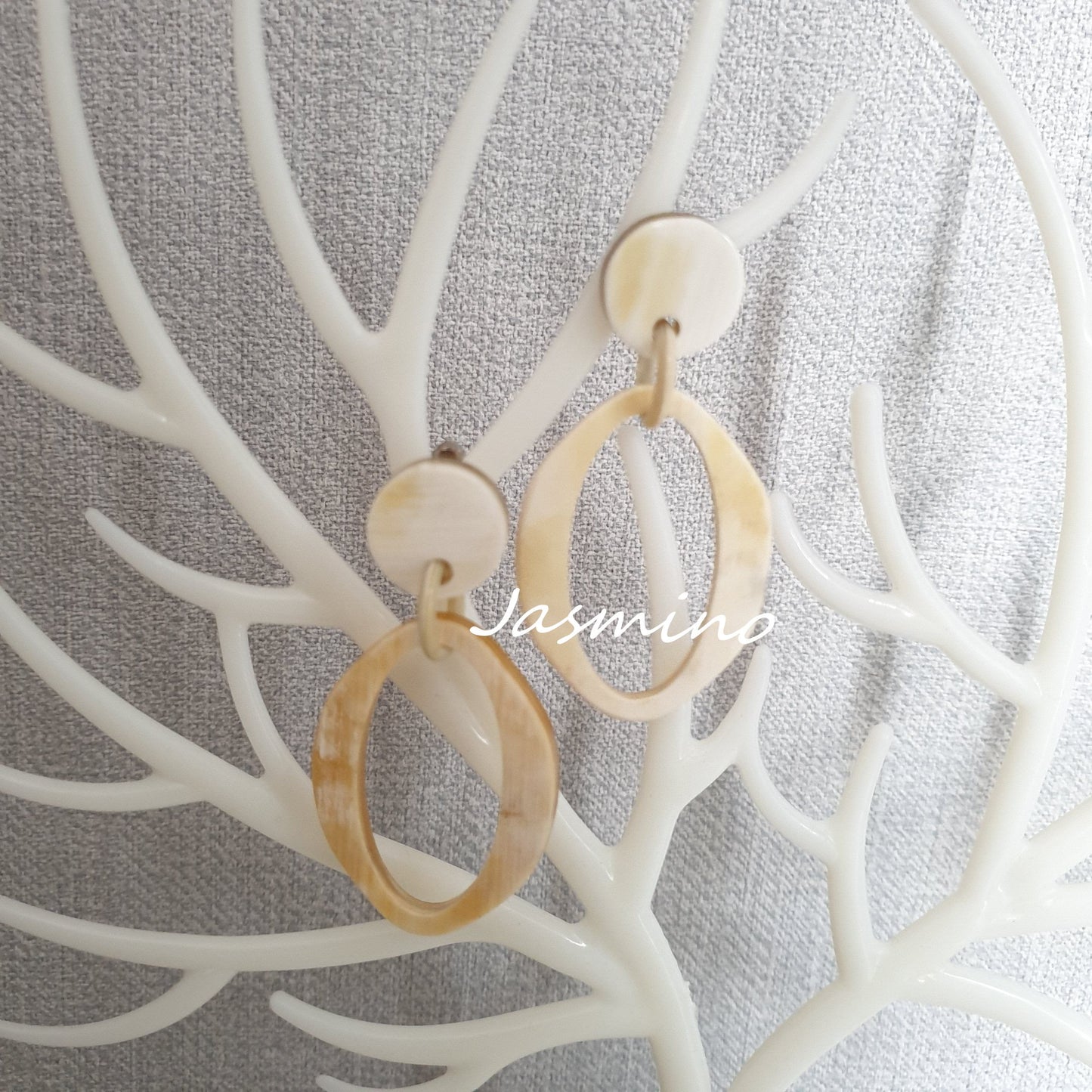 Jasmino elliptical drop earrings feature white and natural buffalo horn material in the natural light