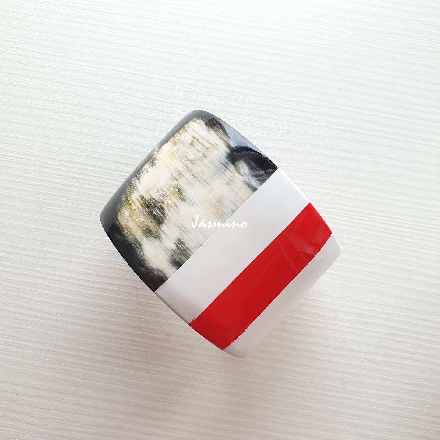 natural buffalo horn bracelet with red stripe on brilliant white painted background, an impressive gift for your friend