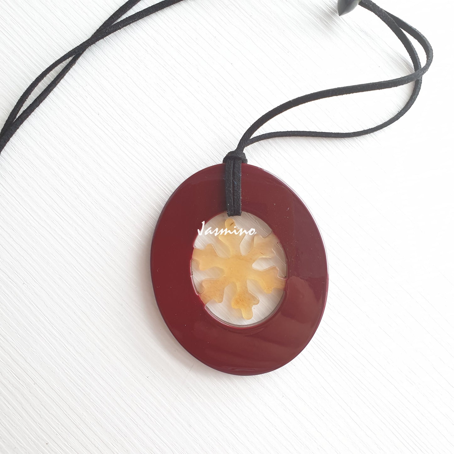 Elliptical cherry pendant with snowflake pattern inside on the light background, impressive Christmas gift for her