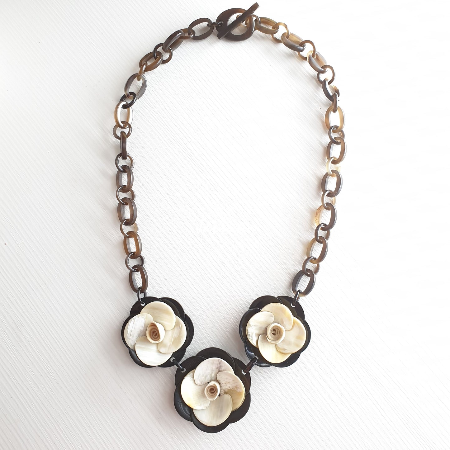 natural buffalo horn necklace with three white flowers centered in natural light