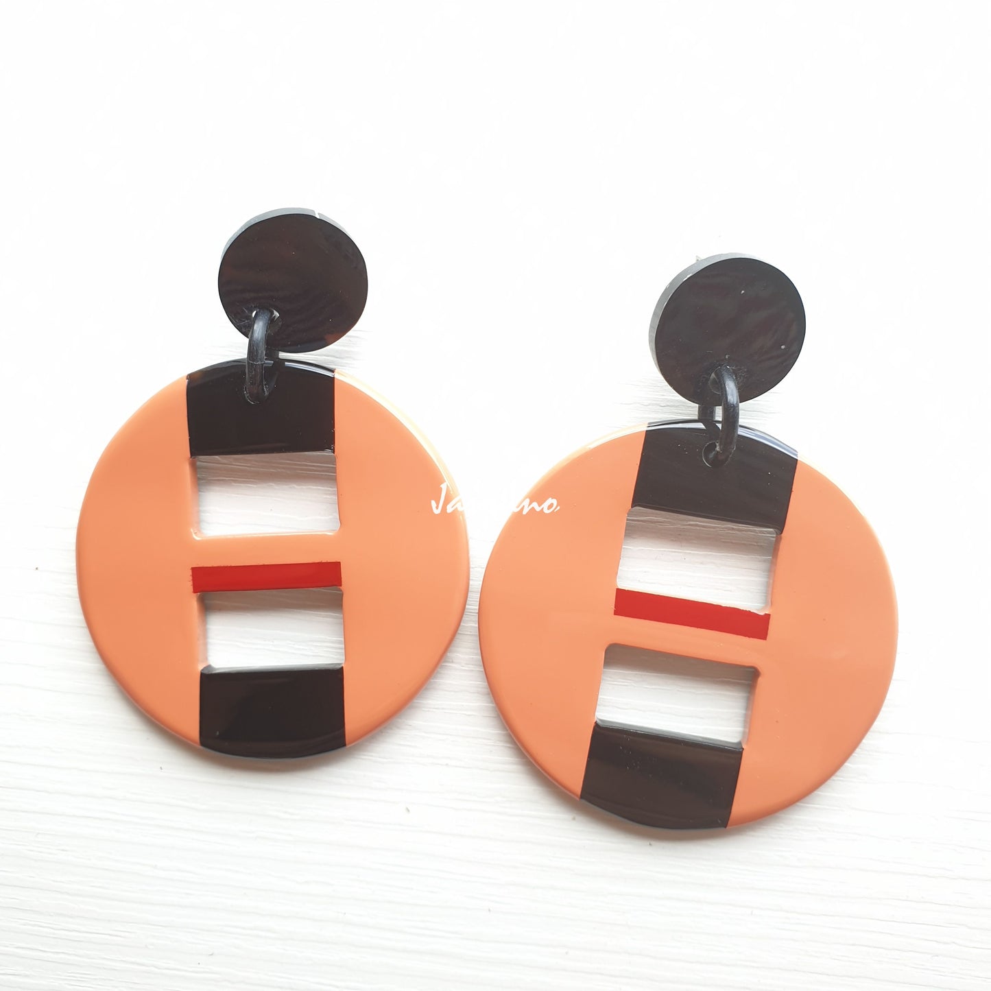 Handmade circular drop earrings feature salmon color with natural buffalo horn on a light background