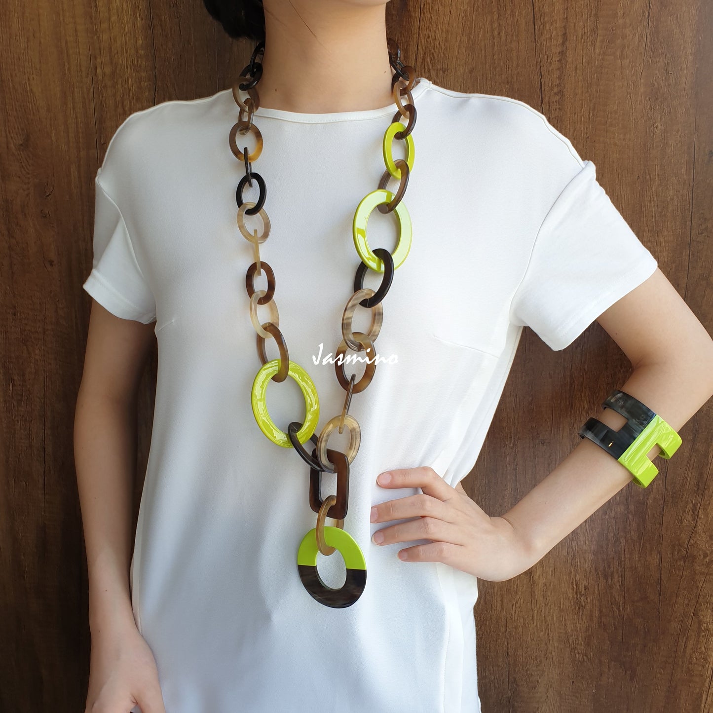 A female model is wearing a collection of a handmade wide chain necklace and cuff bracelet in the natural light 