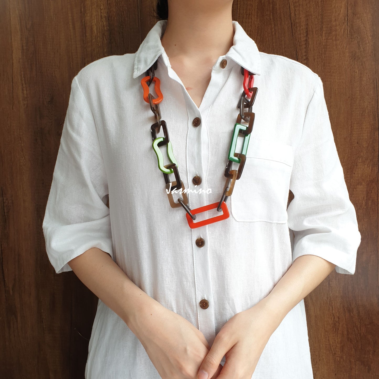 A model is wearing unique handmade necklace featured some large pieces of different colors on a light background, a unique gift for your friend