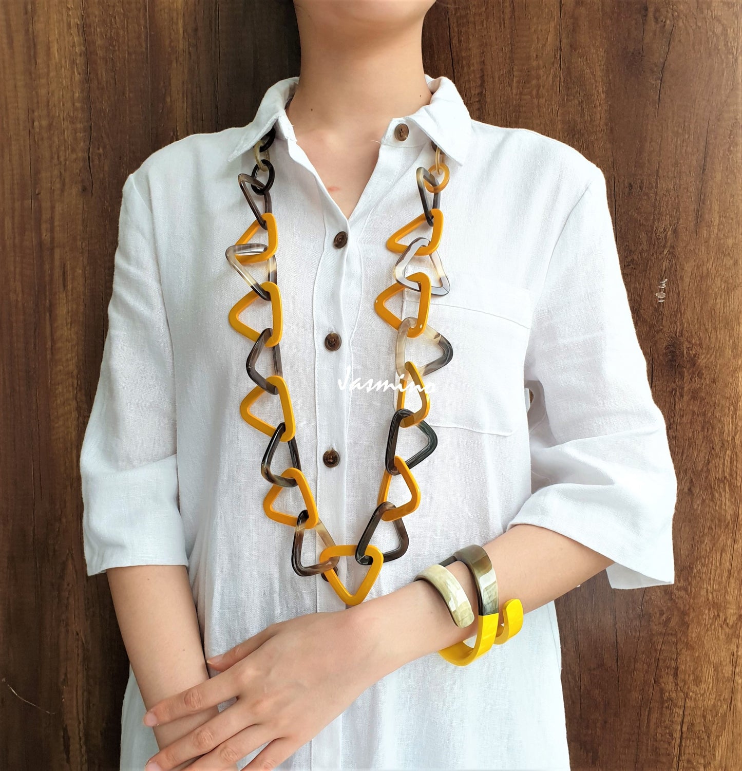 A girl is wearing yellow lacquered triangular pieces and a snake cuff bracelet in the natural light