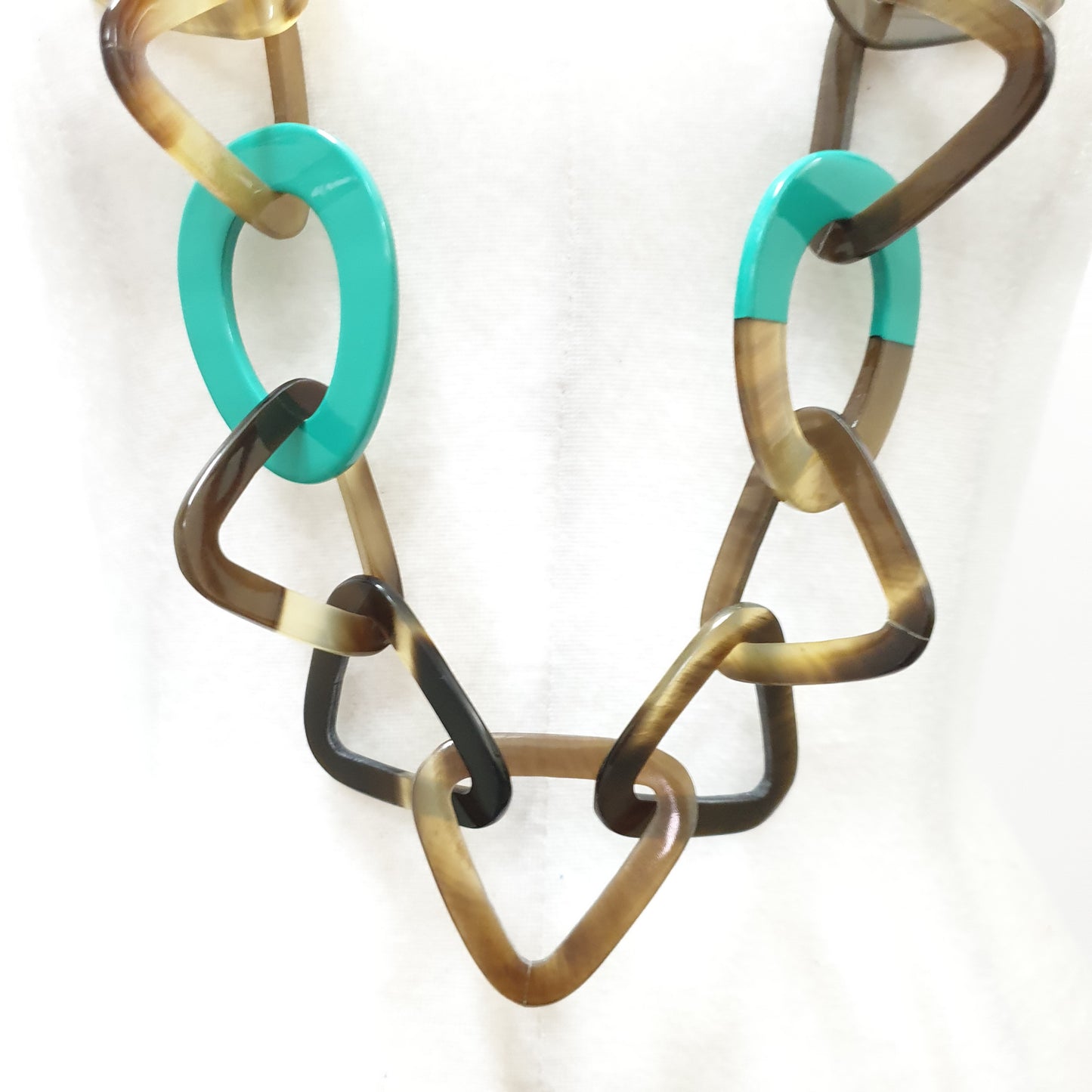 This necklace has several turquoise lacquered elliptical pieces on a light background, a unique gift for your friend