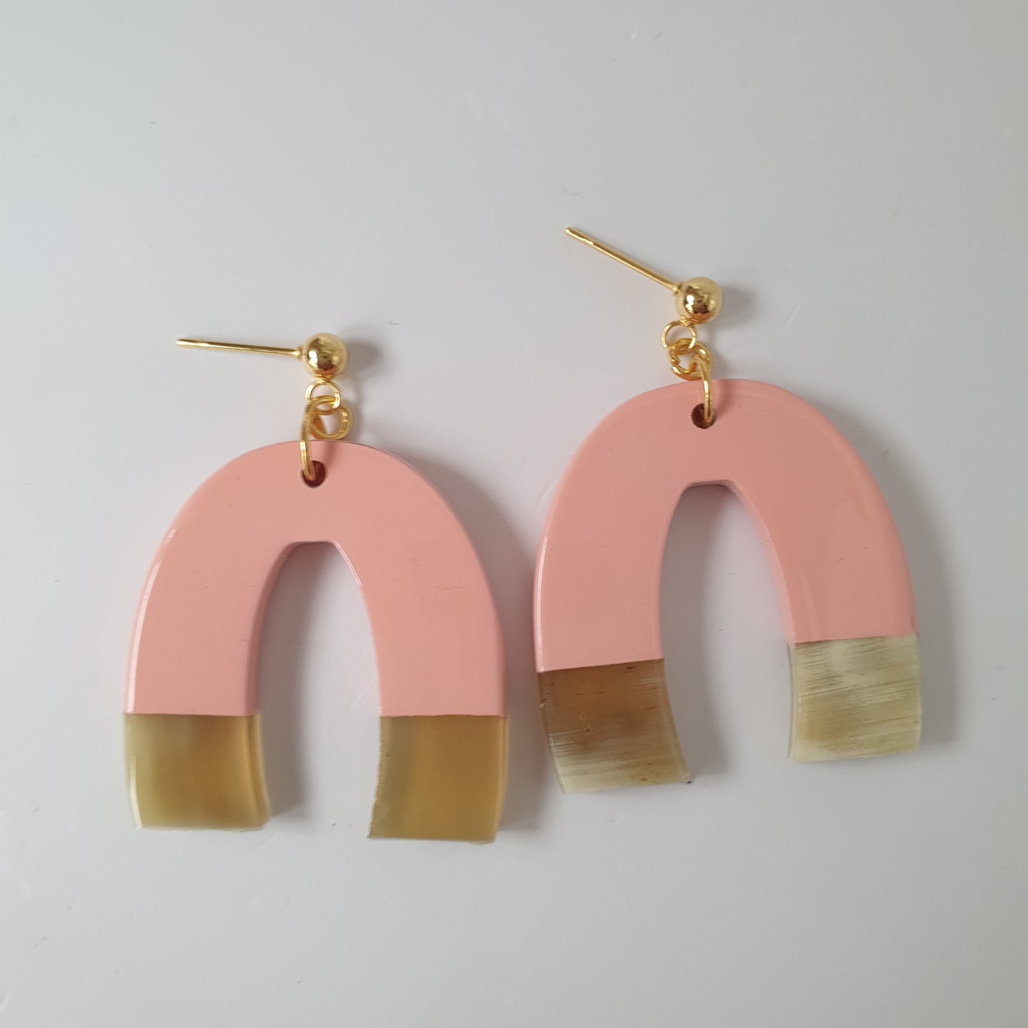 Bestselling pink U-shaped drop earring are handmade with natural buffalo horn material on  a white background