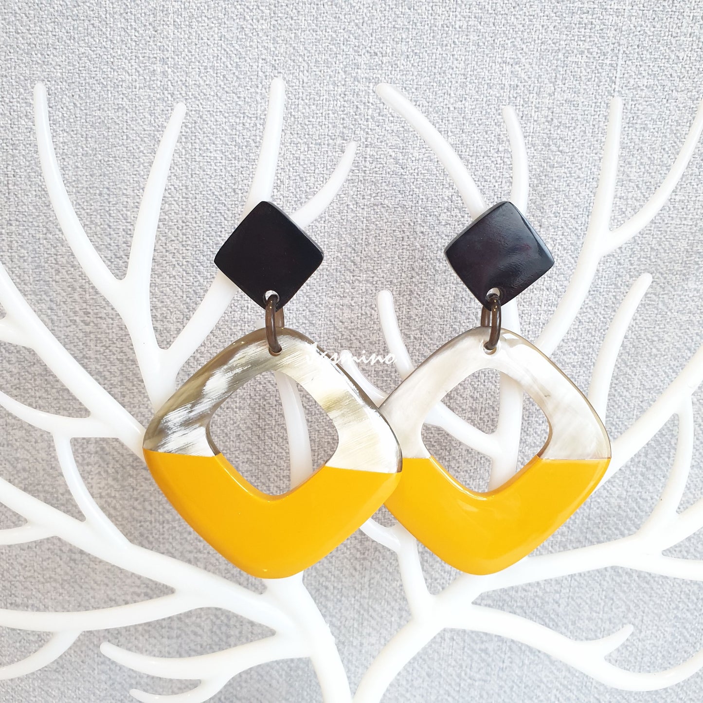 Drop earrings are designed with the top half of a natural buffalo horn and the bottom half is painted vibrant yellow 